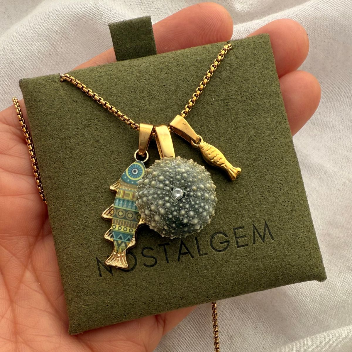 Kina and fish charm necklace worn on model