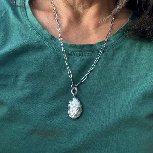 Ocean floor diorama necklace close-up showing rams horn squid shell and coral
