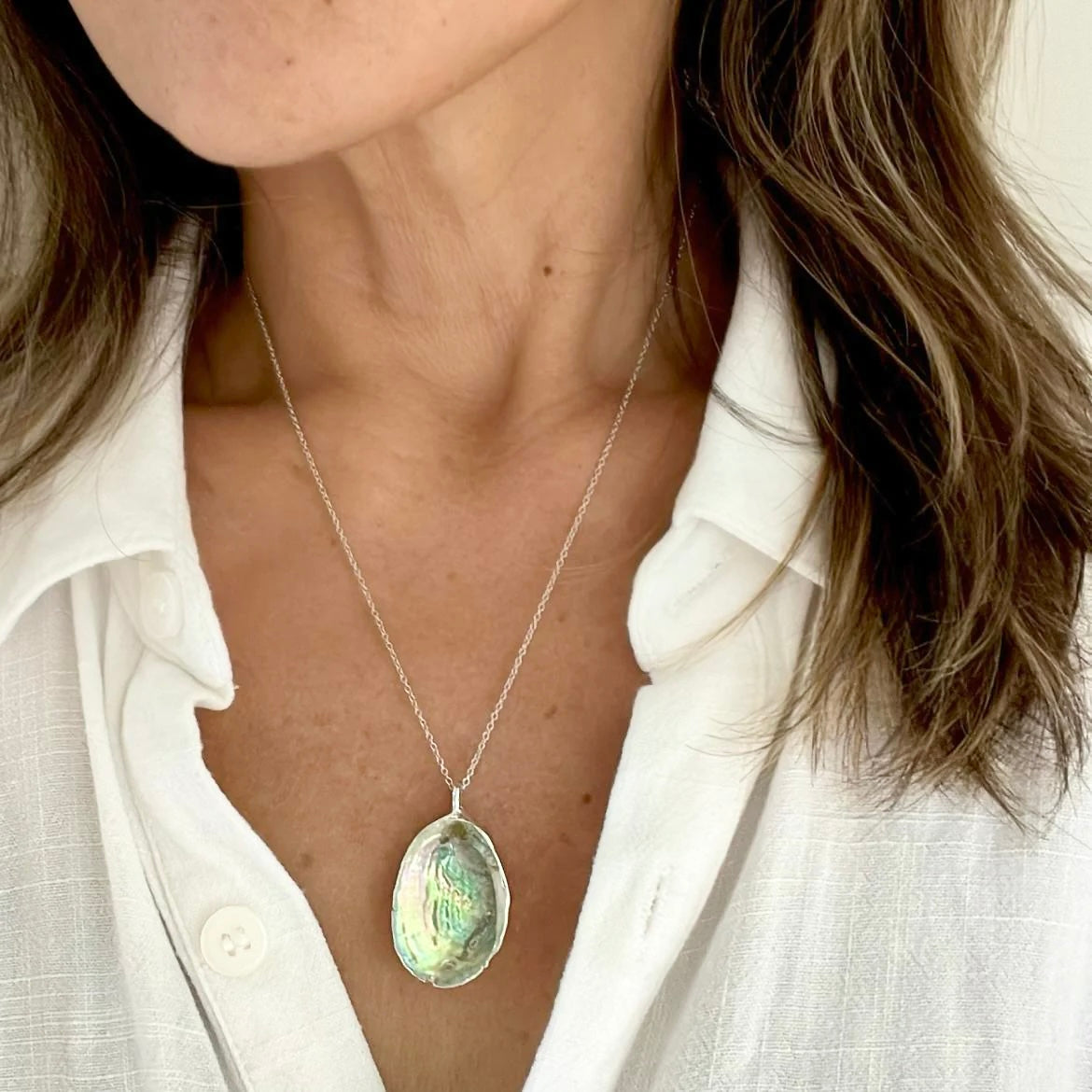 Paua shell silver pendant necklace worn close-up