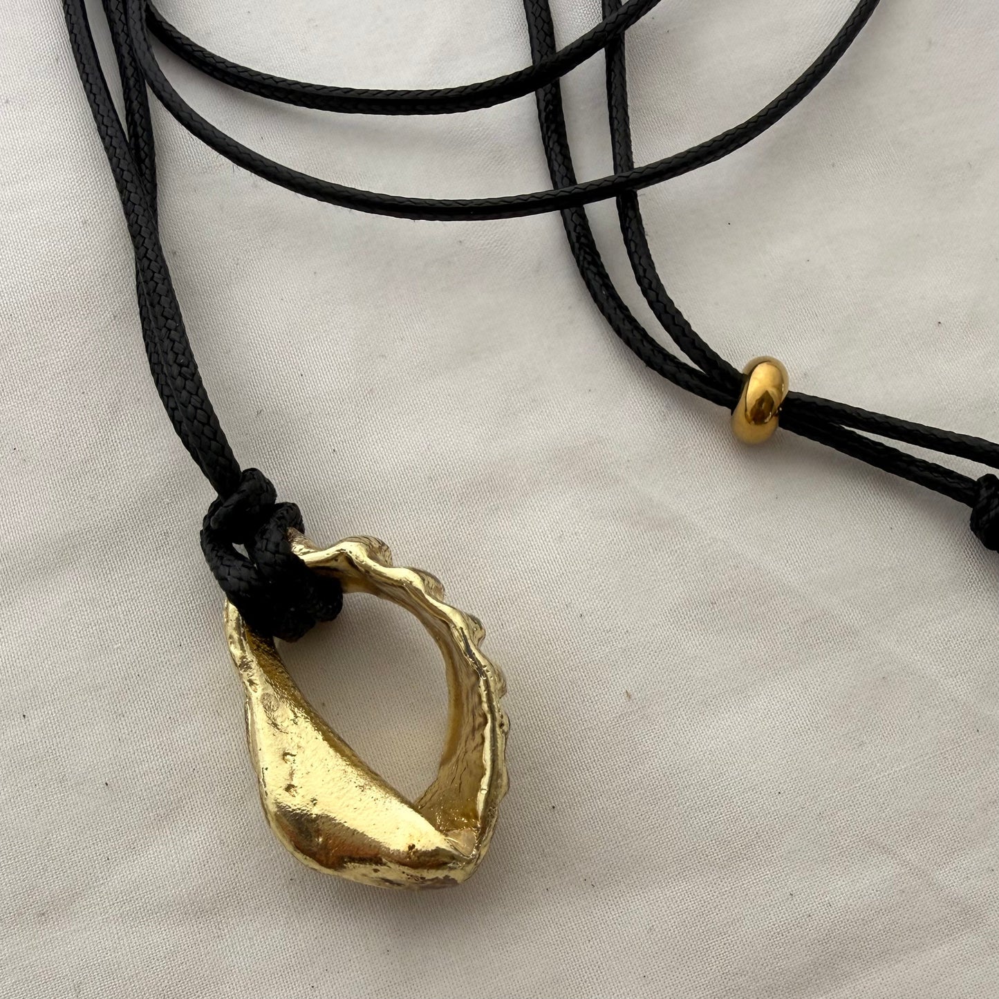 Gold whelk shell cord necklace worn on model